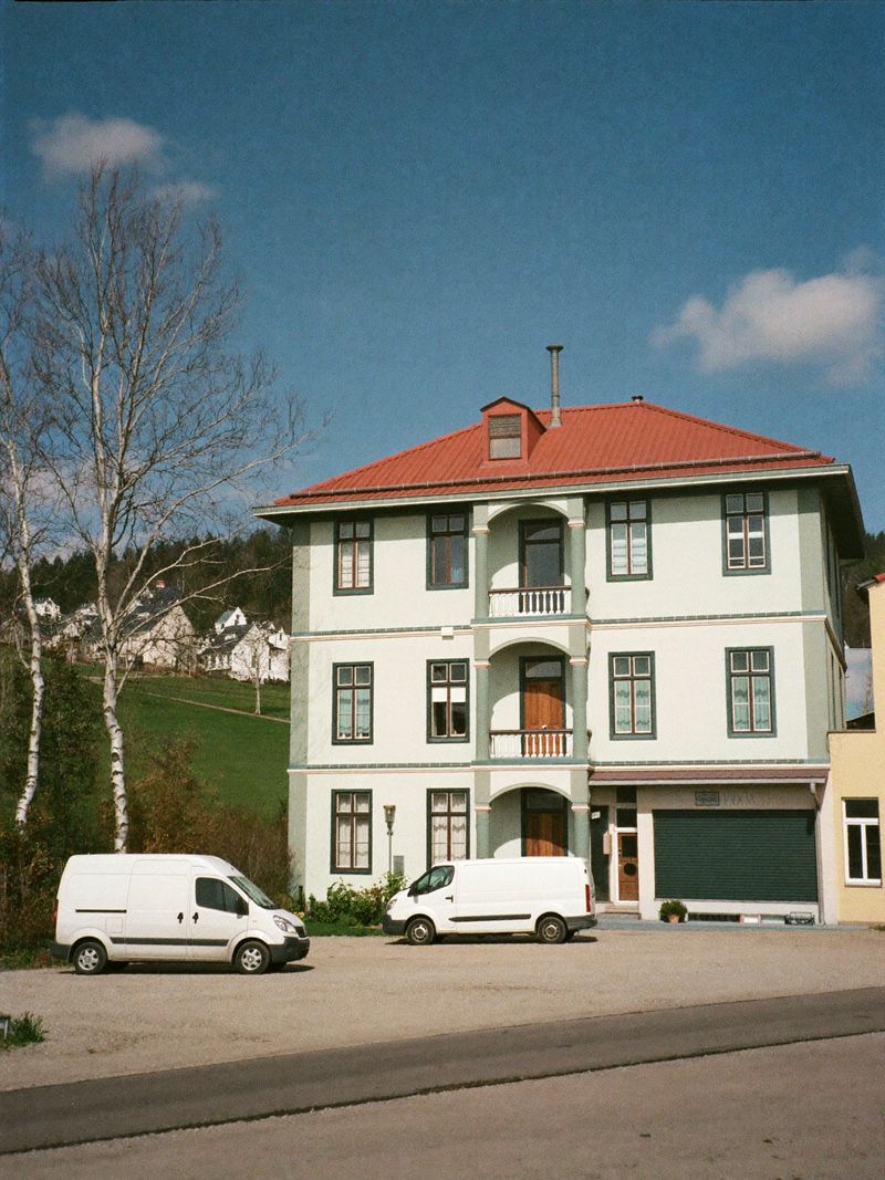 Renoviertes Gästehaus mit rotem Dach und zwei weißen Transportern auf dem Hof