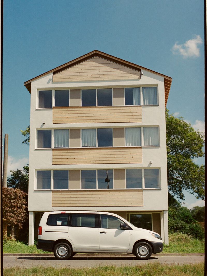 Modernes Aparthotel mit Holzfassade in einem grünen Vorort